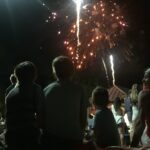 kids sitting on a dock watching 4th of July fireworks at Baytowne Wharf