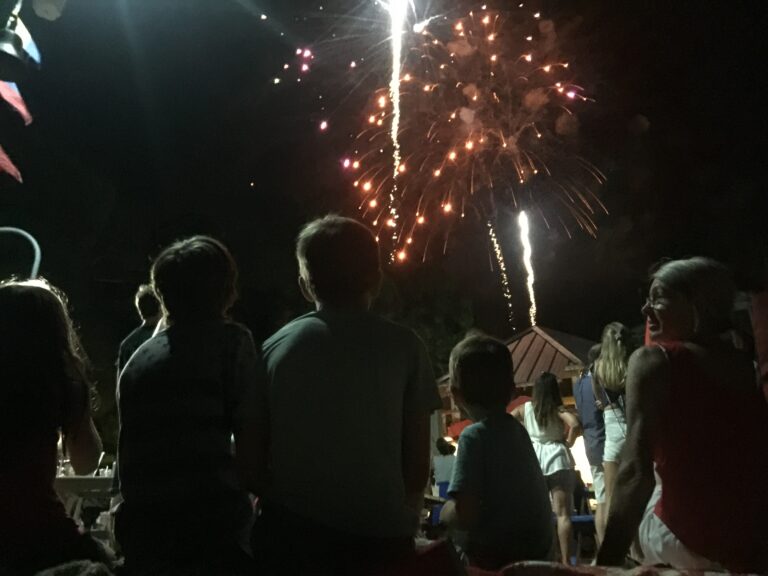 kids sitting on a dock watching 4th of July fireworks at Baytowne Wharf